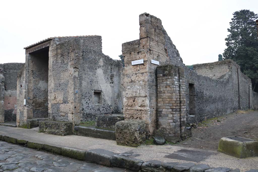 Street altar outside II.2.1 Pompeii. December 2018. 
Entrance doorway, centre left, on south side of Via dellAbbondanza, with street altar in front, and water tower in Vicolo di Octavius Quarto, on right. 
Photo courtesy of Aude Durand.
