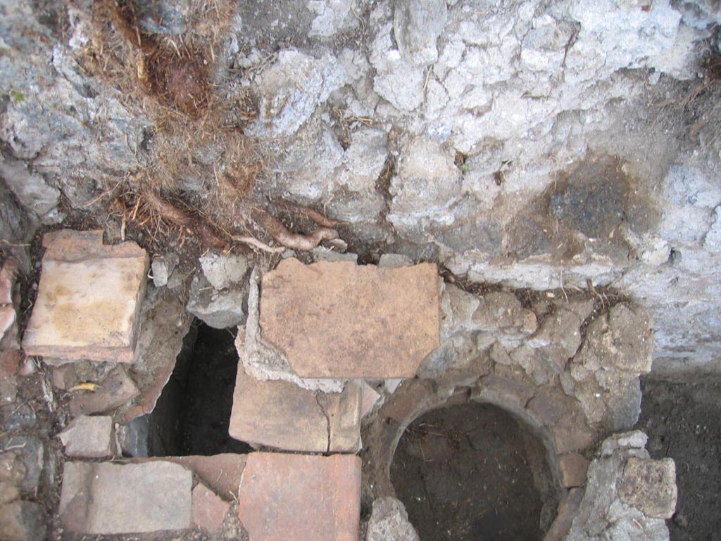 VIII.7.10 Pompeii. August 2005. Looking down onto hearth against south wall in kitchen.
The remains of the niche of the lararium may be still partially visible in the wall above the hearth, upper centre of photo.
Photo courtesy of Pompeii Archaeological Research Project: Porta Stabia.
Site of kitchen, described by Eschebach as having hearth, well and lararium.
See Eschebach, L., 1993. Gebäudeverzeichnis und Stadtplan der antiken Stadt Pompeji. Köln: Böhlau. (p. 389).

