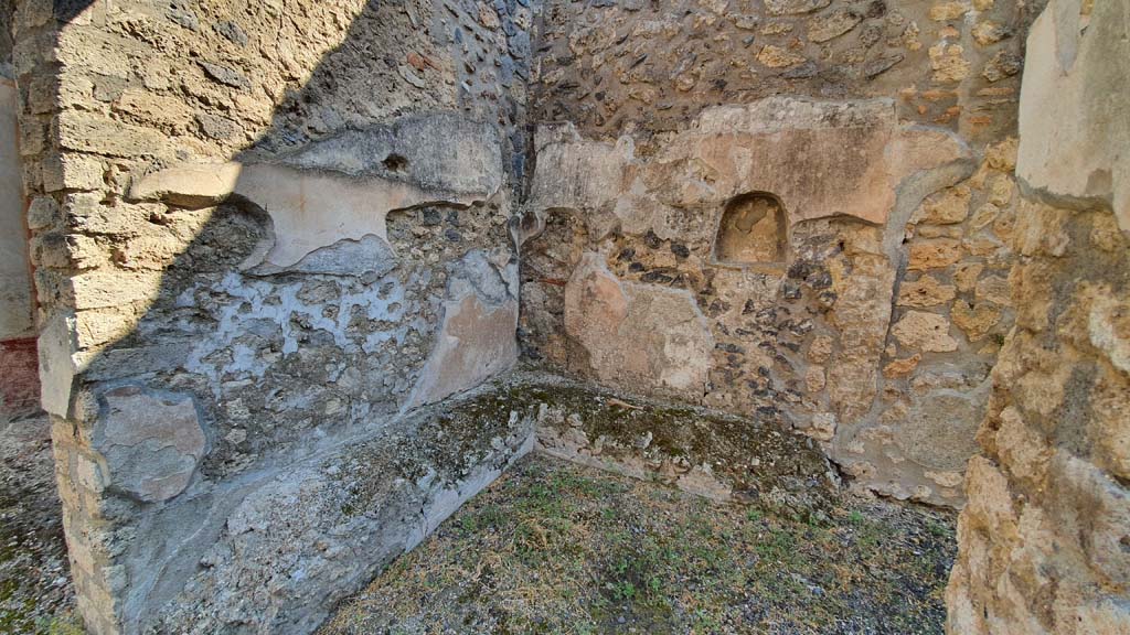 I.11.1 Pompeii. July 2021. 
Room in south-east corner of bar-room with benches for the clients against the north and east walls and a lararium niche in the east wall.
Foto Annette Haug, ERC Grant 681269 DÉCOR.
According to PPM –
“After the fall (between 1977 and 1979) of the last layer of white plaster, the ancient painting of the Genius with a veiled head, sacrificing to the altar, had reappeared. The face of the genius had already been stolen before 1977.”
See Carratelli, G. P., 1990-2003. Pompei: Pitture e Mosaici: Vol. II. Roma: Istituto della enciclopedia italiana, (p.513).
