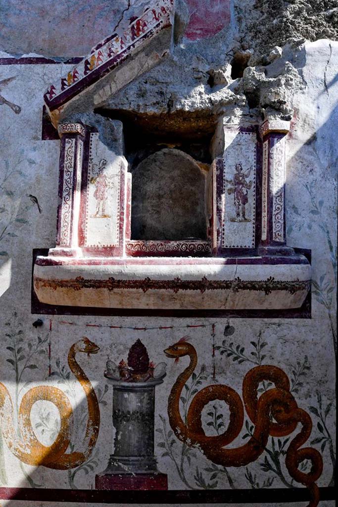 V.3.13 Pompeii. 2018. Room 2a. Lararium. East wall.
Sacred shrine with figures of the Lares painted on the sides and serpents below.

Parete est. L'edicola sacra con ai lati dipinte le figure dei "Lari, e, al di sotto, due grandi serpenti "agatodemoni".

Photograph © Parco Archeologico di Pompei.

