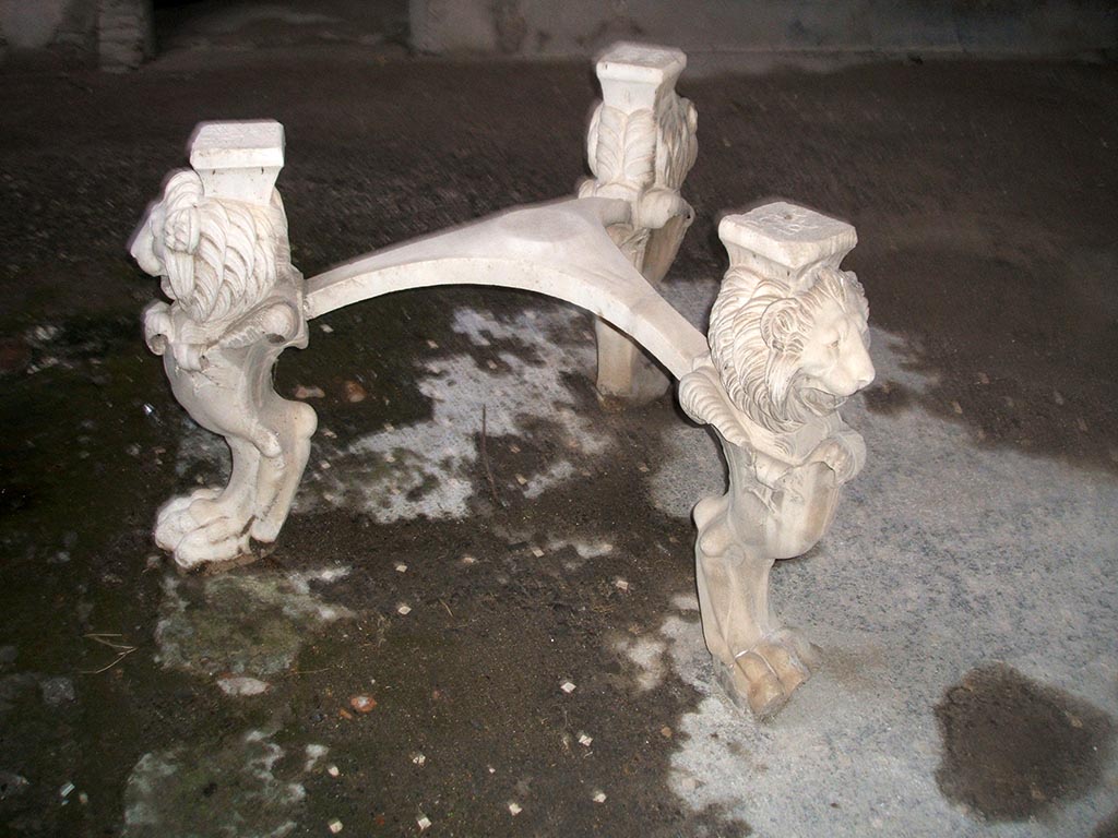 I.6.11 Pompeii. December 2004. Atrium. Marble tripod table legs with lion heads and paws. Inventory number 3921. 
This house was named the Casa di P. Casca Longus from the inscription on the top of these table legs. 
They were found in garden of House I.6.8-9 and moved to I.6.11 by the excavators. 
See Carratelli, G. P., 1990-2003. Pompei: Pitture e Mosaici: Vol. I. Roma: Istituto della enciclopedia italiana. (p. 369). 
According to Allison, this name is unsubstantiated, see http://www.stoa.org/projects/ph/house?id=3. 
