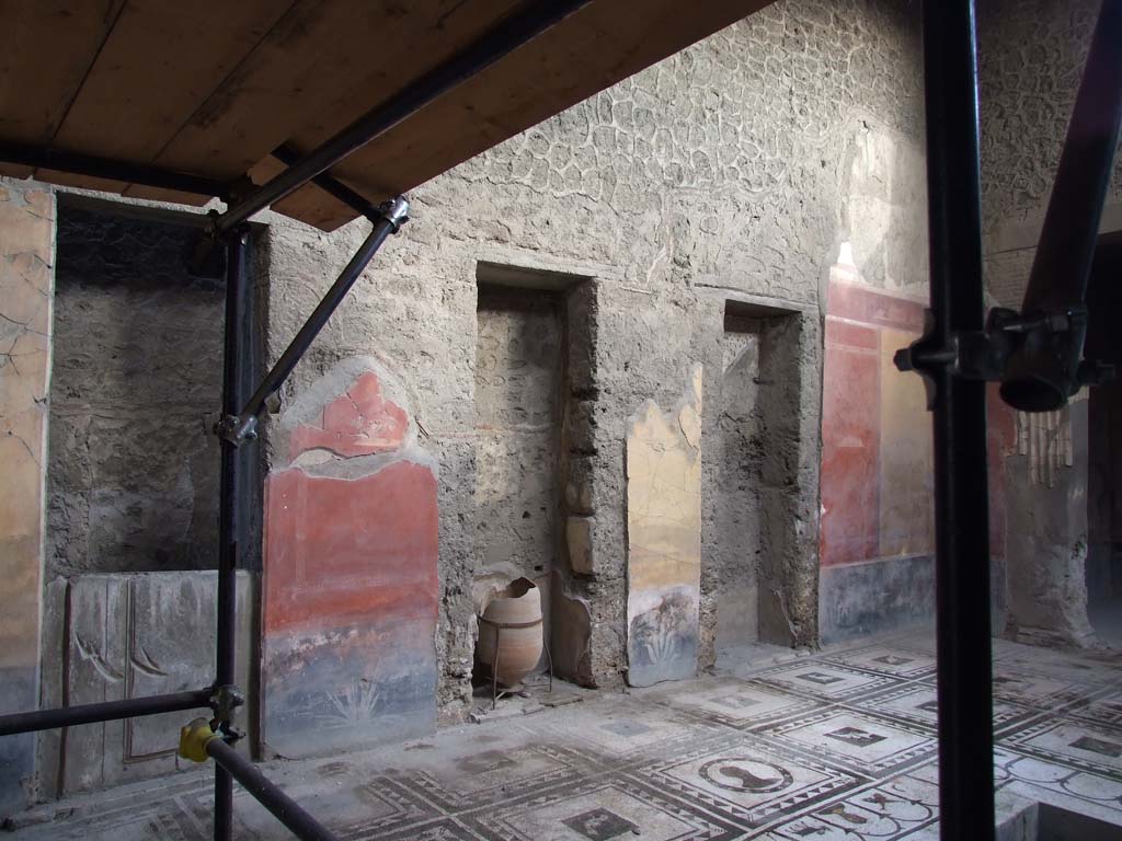 I.7.1 Pompeii. December 2006. Plaster-cast of doorway (on left) and two niches in east wall of atrium.
On the red wall panel, centre left, was a vignette of a glass vase with fruit, photographed, see above.
Below the red panel, the black zoccolo had a painted plant.
