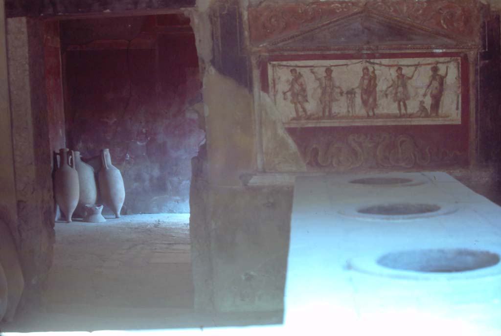 I.8.8 Pompeii. August 1976. Looking south across top of counter towards lararium, on right.
Doorway to rear room, on left. Photo courtesy of Rick Bauer, from Dr George Fay’s slides collection.
