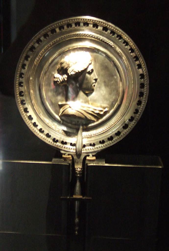 I.10.4 Pompeii. Richly decorated silver mirror with the bust of young woman in the centre. Part of the 115 pieces of Silver found in a chest in the underground storerooms. Now in Naples Archaeological Museum. Inventory number 145525. See Guzzo, P. (A cura di), 2006. Argenti a Pompei. Milano, Electa. p.223.