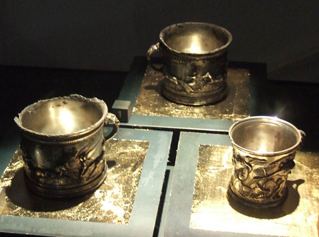 I.10.4 Pompeii. Silver modioli. The left two are decorated with games and the one on right with animals. 
Part of the 115 pieces of Silver found in a chest in the underground storerooms. 
Now in Naples Archaeological Museum. Inventory numbers 145510 (centre) 145511 (left) and 145512 (right).
See Guzzo, P. (A cura di), 2006. Argenti a Pompei. Milano, Electa. p.202-3.
