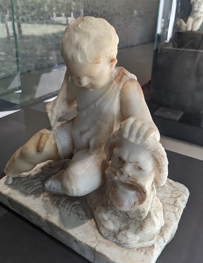 II.2.2 Pompeii. April 2022. 
Room “l”, (L), garden. White marble statuette of a cupid with a mask. On display in exhibition in Palaestra.
Photo courtesy of Giuseppe Ciaramella.
