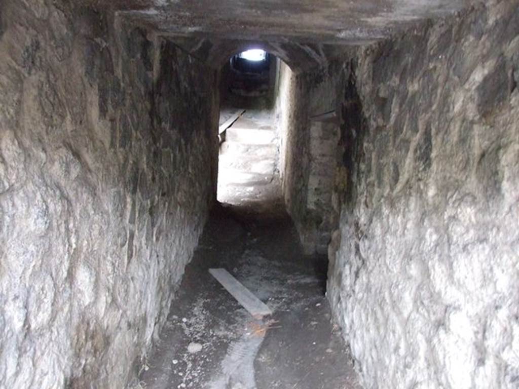 II.6 Pompeii. December 2006. Tunnel leading from arena floor to outside the Amphitheatre. According to Mau, this narrow and low passageway was the gruesome corridor where the bodies of the dead were taken. They were removed from the arena and dragged by means of hooks, its entrance was the Porta Libitinensis, “Death Gate”. On the right can be seen a doorway to another dark room, possibly a storeroom in the corridor. At the far end is a doorway in the exterior west wall of the Ampitheatre. See Mau, A., 1907, translated by Kelsey, F. W., Pompeii: Its Life and Art. New York: Macmillan. (p. 215).