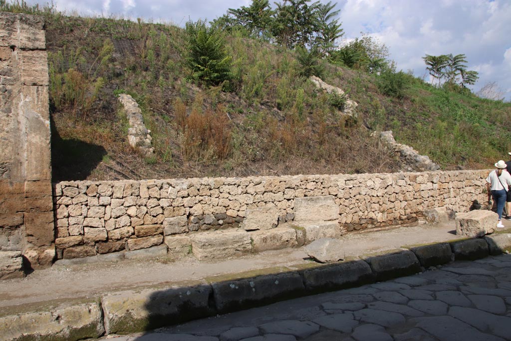 III.7.1, on left, Pompeii. October 2022. Continuation from photo above – the entrance doorway with threshold, on left.
The large square blocks, presumably from the ruined wall on the east side of the doorway or the seat/bench outside, have now been re-laid. 
Photo courtesy of Klaus Heese
According to CTP –
“Conspicuously evident together with the low masonry seat, is the window to the east of the entrance in Della Corte’s photograph (NSA 1936, p.333, fig.10).
The photograph clearly reveals the doorway at No.1. The wall to the east of the entrance has now collapsed.”
See Van der Poel, H. B., 1986. Corpus Topographicum Pompeianum, Part IIIA. Austin: University of Texas. (p.64).
