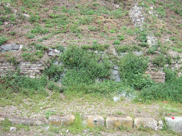 IV.1.g  Pompeii. May 2005.  Entrance.

The doorways that used to front onto the northern side of Via Nola, forming Regio IV, have now been filled in as a wall to keep the earth bank back from the road.  It is very difficult to find the exact position of these doorways and link them to any site plan.