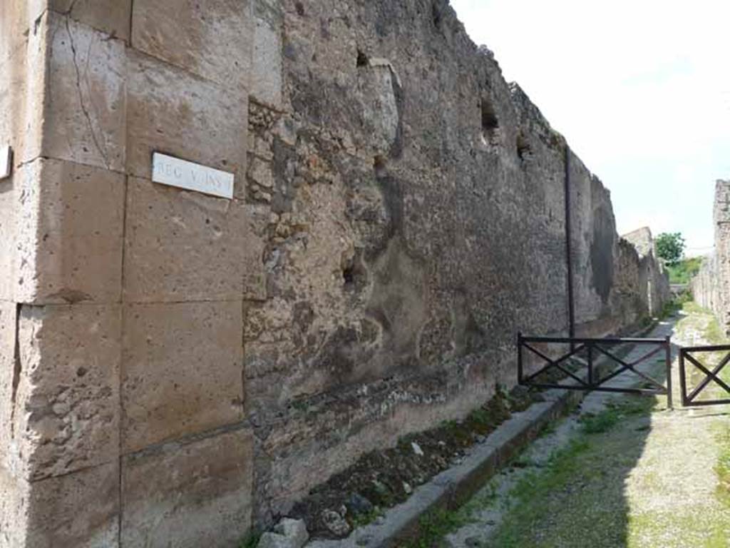 V.1.8 Pompeii. May 2010. 
Exterior of east wall of shop on west side of Vicolo di Cecilio Giocondo, looking north from junction with Via di Nola.
