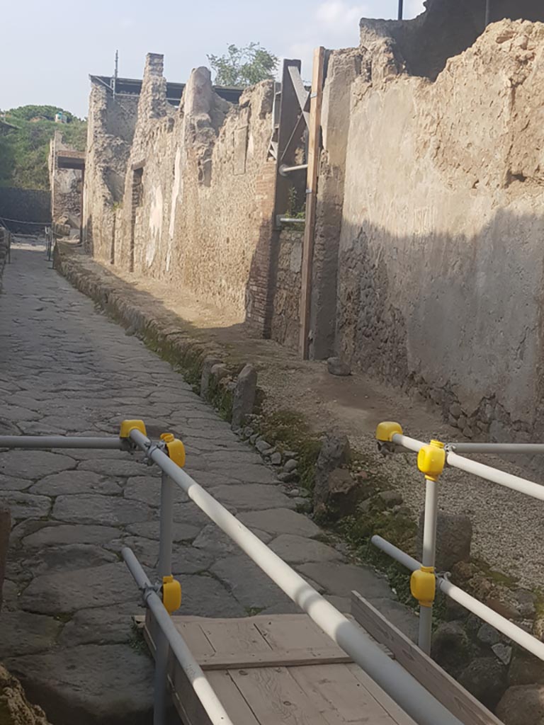 Vicolo dei Balconi, Pompeii. October 2022. 
Looking north along east side of roadway. Photo courtesy of Klaus Heese.
The house entrances (now blocked) we number as B5, B4 and B3. The balcony of B1 is at the junction but B2 is not visible in this photo.

