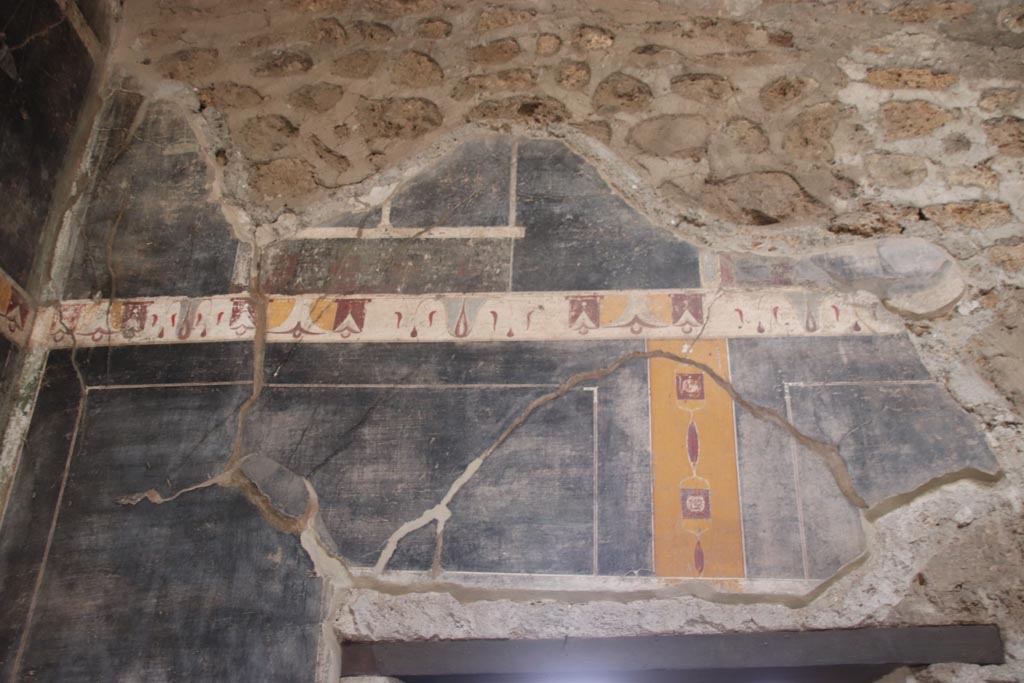 V.4.a Pompeii. October 2023. 
Upper south wall of atrium in south-east corner, detail of painted decoration above doorway to room ‘g’. Photo courtesy of Klaus Heese.
