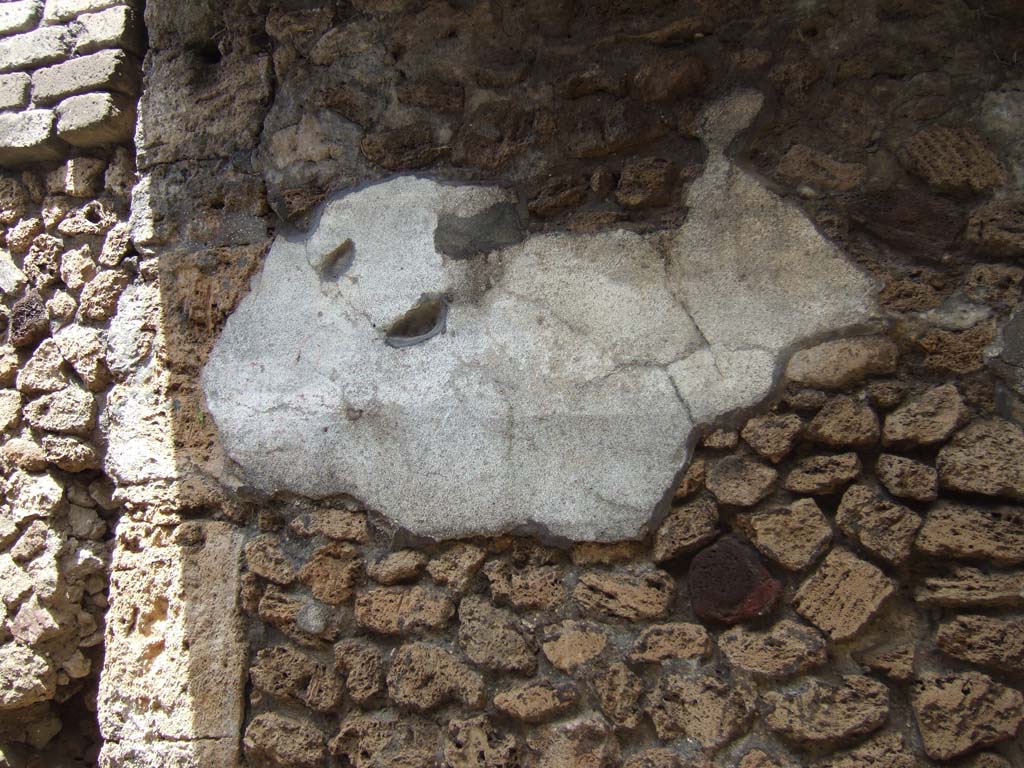 V.7.5 Pompeii. May 2006. Remains of painted plaster on east side of doorway.