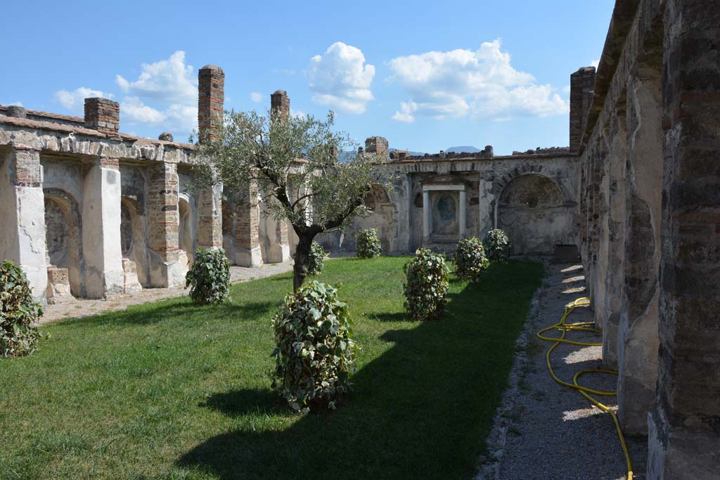 VI.10.7 Pompeii. September 2019. Looking south from north end.
Foto Annette Haug, ERC Grant 681269 DÉCOR.
According to the PAP information card in this house –
“The garden area is enclosed on three sides by a cryptoporticus (covered corridor). 
In one of the phases in which the house was built, the short side at the end of the garden was embellished with an aedicula (tabernacle) flanked by two fountains and niches set between the arches of the cryptoporticus. 
The three rooms opening onto the upper terrace at the north end had the benefit of the view of this splendid porticoed viridarium with its aedicula.”


