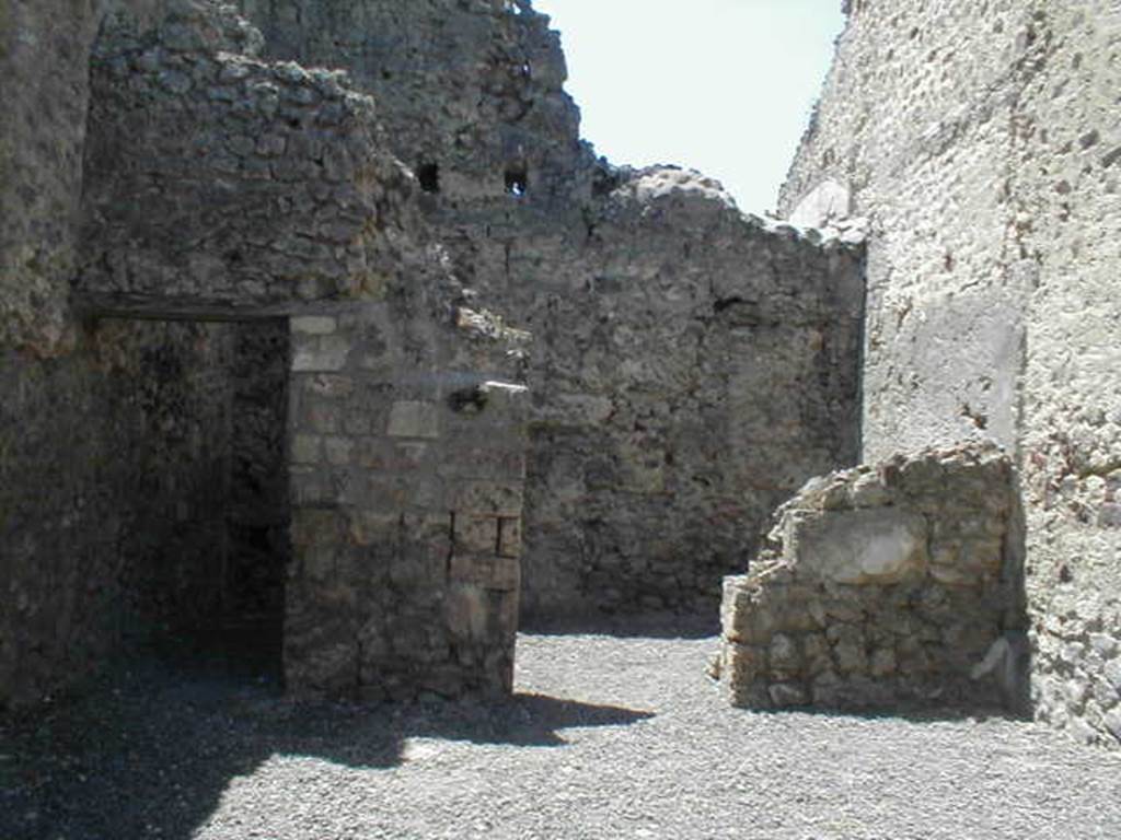 VI.14.24 Pompeii. May 2005. Looking west across shop to doorways to two rear rooms.
According to BdI, on the right of the shop entrance in the north-east corner, was a small hearth, and in the same corner was a latrine. Objects found in the shop were a bell, various pots, five keys and a few bronze coins. The rear room on the right was the biggest. 
Upon excavation, the walls of the upper rooms were also preserved, one above the rear rooms, the other above the shop-room. This last wall, with pink coloured plaster until the height of approximately 1.50m, unpainted above, and with a large window onto the roadway.  It was evident that these two rooms joined by a doorway between them, formed a separate complex from the rest of the house, and that this could be rented independently from the shop below. See Bullettino dellInstituto di Corrispondenza Archeologica (DAIR), 1876, (p.44)
