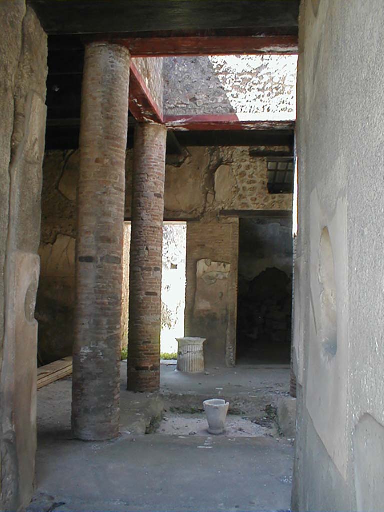 VI.15.9 Pompeii. September 2004. Entrance corridor, looking west to atrium.
According to Richardson, this tiny atrium house had a very efficient design.
The atrium is entered by short fauces flanked by cubicula with windows to the street.
The atrium is almost square, Tetrastyle with columns of naked brick that supported a second floor.
The second floor was a gallery lit by large rectangular windows into the compluvium well.
It was accessible by a small staircase against the north wall of the atrium.
Although it must have made the atrium rather dark, it made living space available over the atrium, as well as over the cubicula at the front of the house.
On the far side of the atrium, opened an ample triclinium and the service area.
This service area in the south-west corner of the house was lit by a second light-well and had a second storey of its own, possibly just a loft for storage.
See Notizie degli Scavi di Antichità, 1897, 38-39, 62-64.
See Richardson, L., 1988. Pompeii: An Architectural History. Baltimore: John Hopkins University Press. (p.345-6)
(Note – the staircase is actually against the south wall of the atrium)
