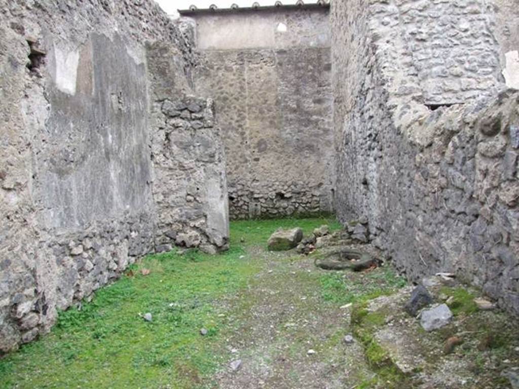 VI.16.5 Pompeii. December 2007. Looking west across shop towards rear room. According to Sogliano in NdS, when first excavated the walls were unadorned.  Leaning against the right of the north wall were the remains of a large masonry feature with two steps before it.
To the right of this same and really in the north-east corner, there seemed to be seen the remains of a fusorium. Towards the other side of the same wall, there was a circular lava cistern mouth, (centre right of photo). See Notizie degli Scav idi Antichit, 1906, (p.350, and plan on p.346).
