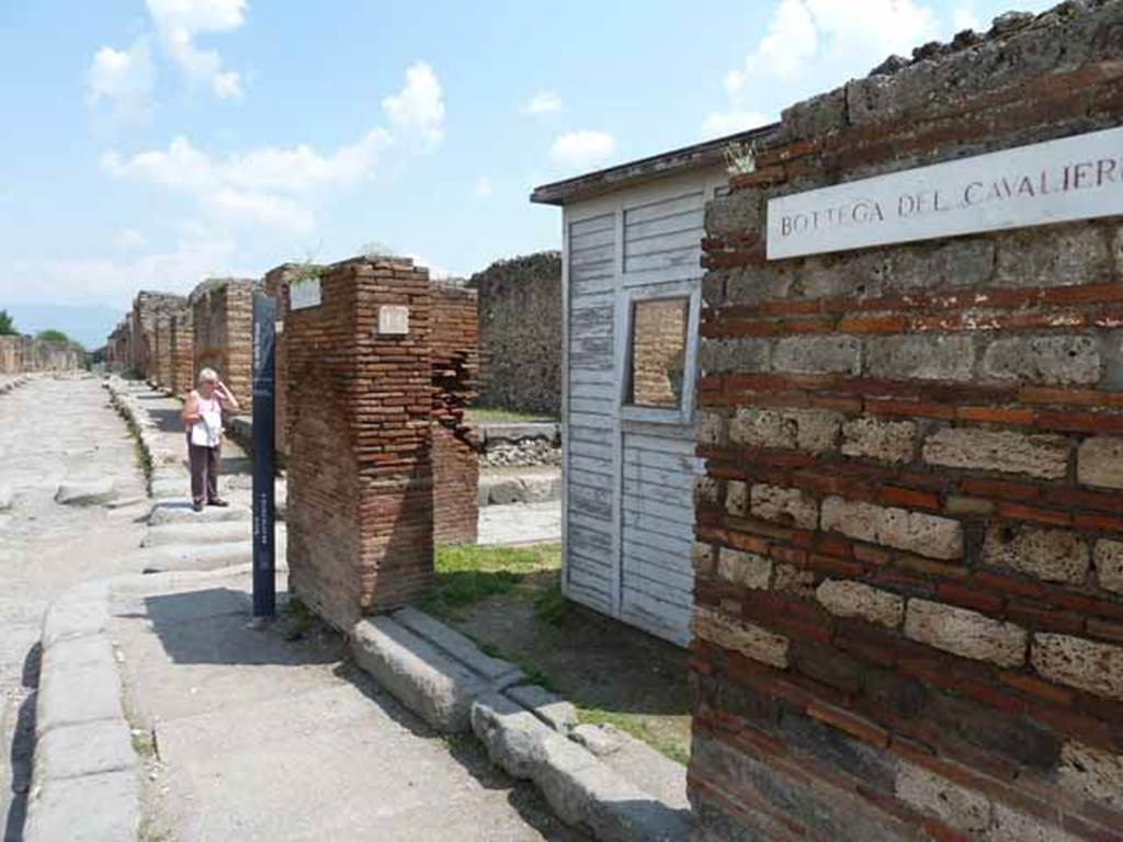 VII.3.14 Pompeii. May 2010. Entrance to shop, looking east across Via Stabiana towards Via di Nola with Bottega del Cavalieri sign.

The tavern (VII, 3, 14-15) was one of the stops of the visit of Pope Pius IX on October 22, 1849, and from where was found, together with a lot of bronze materials and marble fragments, the bas-relief of the galloping cavalier (Museo Profano, Bib. Apostolica Vaticana, inv. 4092), of which there has been much debate about its true Pompeian origin, in a controversy that does not even seem settled after the study made by Conticello (AA.VV., 1987: 31-38, tav. 2) for the catalog of the exhibition twenty years ago dedicated to this visit.
See Uroz Sez J., Uroz Rodrguez H., 2008. Pompeya: Regio VII, Insula 3. Instituto del Patrimonio Cultural de Espaa, p. 60.
