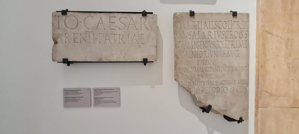 VII.4.1 Pompeii, on left. April 2023. Inscription from Temple, and from Basilica (VIII.1.1) on right. Photo courtesy of Giuseppe Ciaramella.
On display in “Campania Romana” gallery in Naples Archaeological Museum, inv. 3810 on left, and inv. 3770 (from Basilica) on right.

On left: Tempio della Fortuna Augusta (23 febbraio 1824)
[Augu]ṣto Caesari
[Divi f(ilio)], p̣arenti patriae.     [CIL X, 823]

On right: VIII, 1, 1, Basilica (15 agosto 1813)
Martialis C(ai) Oli Primi
M(anius) Salarius Crocus
Primigenius C(ai) Oli Primi
min(istri) Fortunae Aug(ustae)
iussu
Q(uinti) Postumi Modesti C(ai) Vibi Secundi
d(uum)v(irorum) i(ure) d(icundo)
C(ai) Memmi Iuniani Q(uinti) Brutti Balbi aedil(ium)
[L(ucio) D]uvio P(ublio) Clodio co(n)s(ulibus)      [CIL X, 826]
