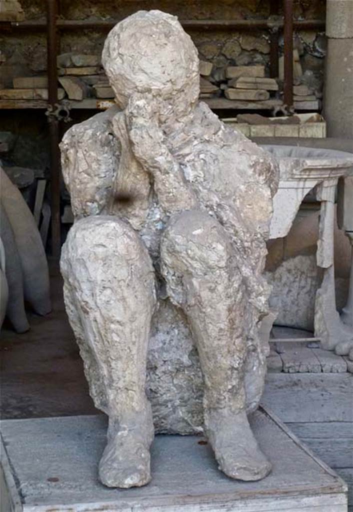 VII.7.29 Pompeii. May 2011. Plaster cast of a figure found near the latrine, perhaps crouching on the ground with his back against the wall of the east portico of the Palaestra at II.7. Photo courtesy of Michael Binns.
According to Stefani, when this body was cast, he was found to be tipped forwards, huddled up and bent double on his knees, when restored he was placed in this position. 
See Stefani, G. (2010). The Casts, exhibition at Boscoreale Antiquarium, 2010. (p.10)

