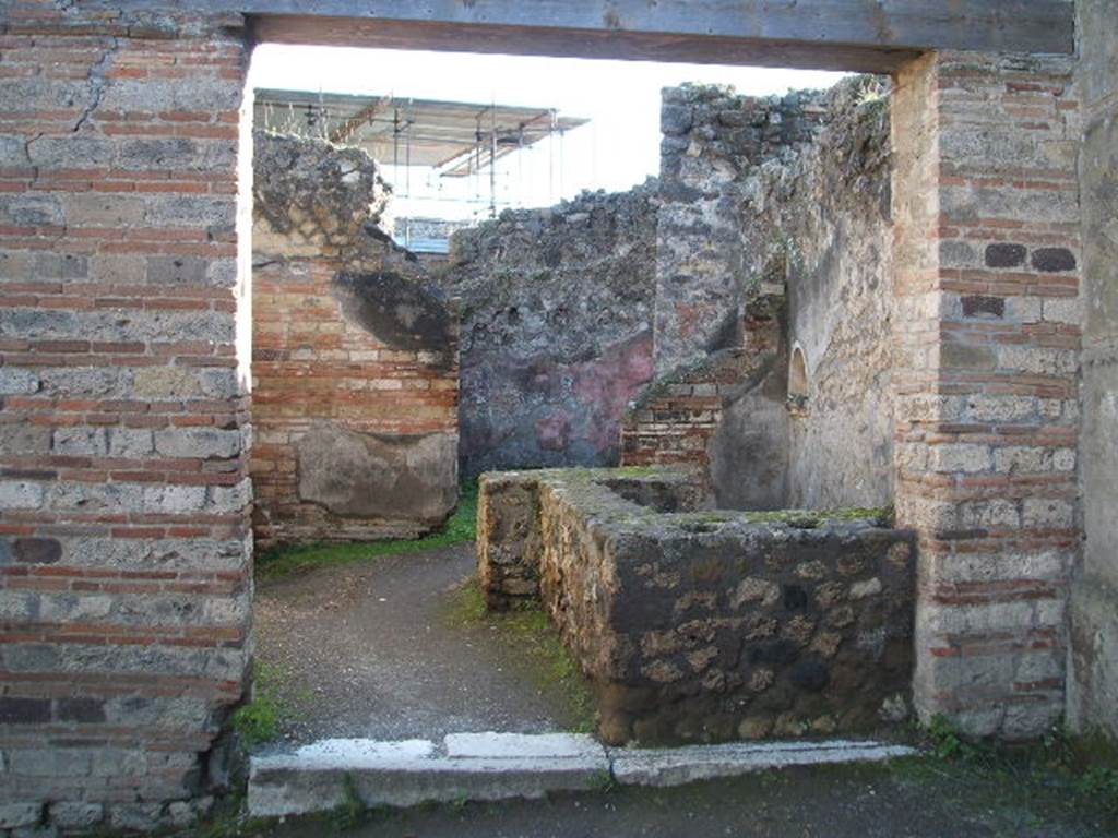 VII.12.15 Pompeii. December 2004. Entrance doorway and counter with hearth, and niche in west wall. At the rear is a doorway to a room used for the hospitality of the guests. See Della Corte, M., 1965.  Case ed Abitanti di Pompei. Napoli: Fausto Fiorentino. (p.202)

