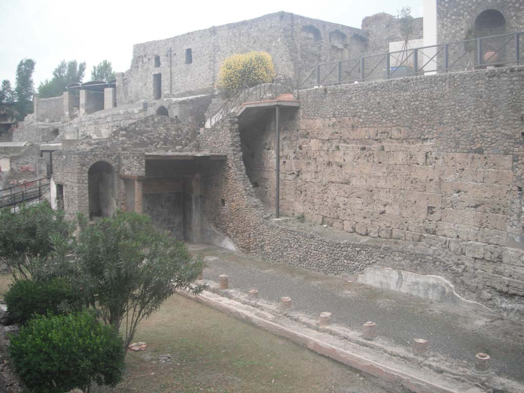 VIII.1.a, Pompeii. May 2010. Looking towards north end of portico, with the original city walls, on right. 
In the north-east corner between the two walls is the location of the outlet. Photo courtesy of Ivo van der Graaff.
According to Van der Graaff –
“Another outlet [of a drain] on the south side of the Porta Marina is part of the outer curtain, indicating a similar if not earlier date. 
The drain likely functioned as an overflow for a system of cisterns set slightly farther uphill, but damage wrought on the area by Allied bombing in World War II makes this claim unverifiable (Note 117). The channel ceased to function with the expansion of the Temple of Venus, when it disappeared behind the masonry of the Villa Imperiale in the course of the first century BCE.”
See Van der Graaff, I. (2018). The Fortifications of Pompeii and Ancient Italy. Routledge, (p.104 & Note 117).

