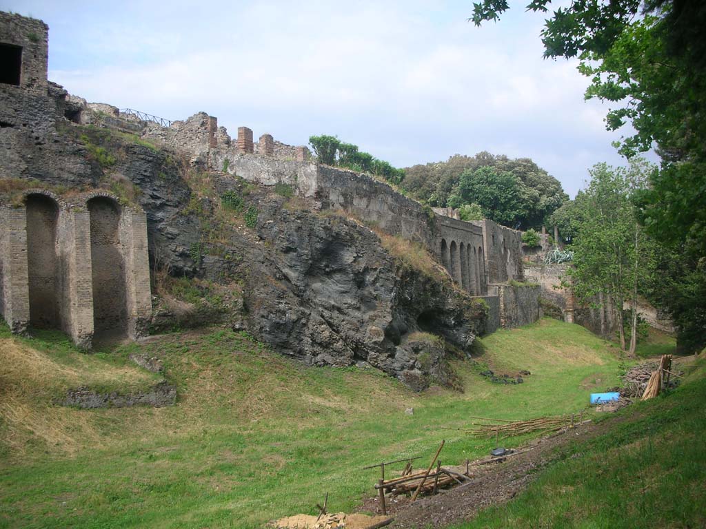 Rear of VIII.2.28, on left, and VIII.2.30 with city wall built on top of volcanic ledge, in centre. May 2011. 
Looking east along rear of “hanging houses”. Photo courtesy of Ivo van der Graaff.
