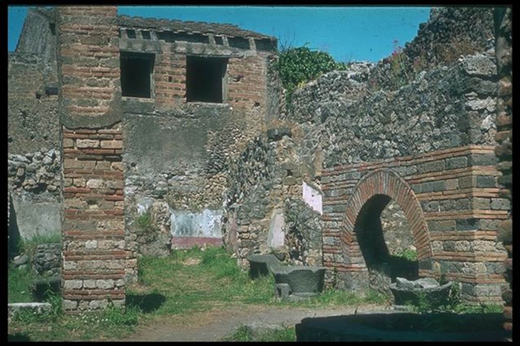 IX.3.12 Pompeii. Looking north-east from entrance. Photographed 1970-79 by Gnther Einhorn, picture courtesy of his son Ralf Einhorn. According to Boyce and Frohlich, the large rectangular pilaster opposite the oven used to be decorated with white stucco to a height of about two metres. See Boyce G. K., 1937. Corpus of the Lararia of Pompeii. Rome: MAAR 14. (p. 83 and pl. 20). See Frhlich, T., 1991. Lararien und Fassadenbilder in den Vesuvstdten. Mainz: von Zabern. (p. 295 and Taf. 45.2)