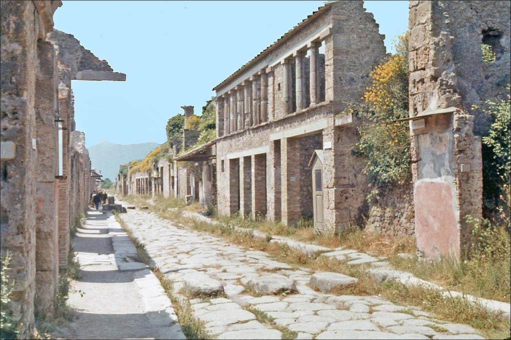 IX.11.8 Pompeii, on left, with graffiti. June 1962. Looking east between IX.12 and 1.8 on Via dell’Abbondanza. 
Photo by Brian Philp: Pictorial Colour Slides, forwarded by Peter Woods
(P43.14 POMPEII House facades along a principal street)
