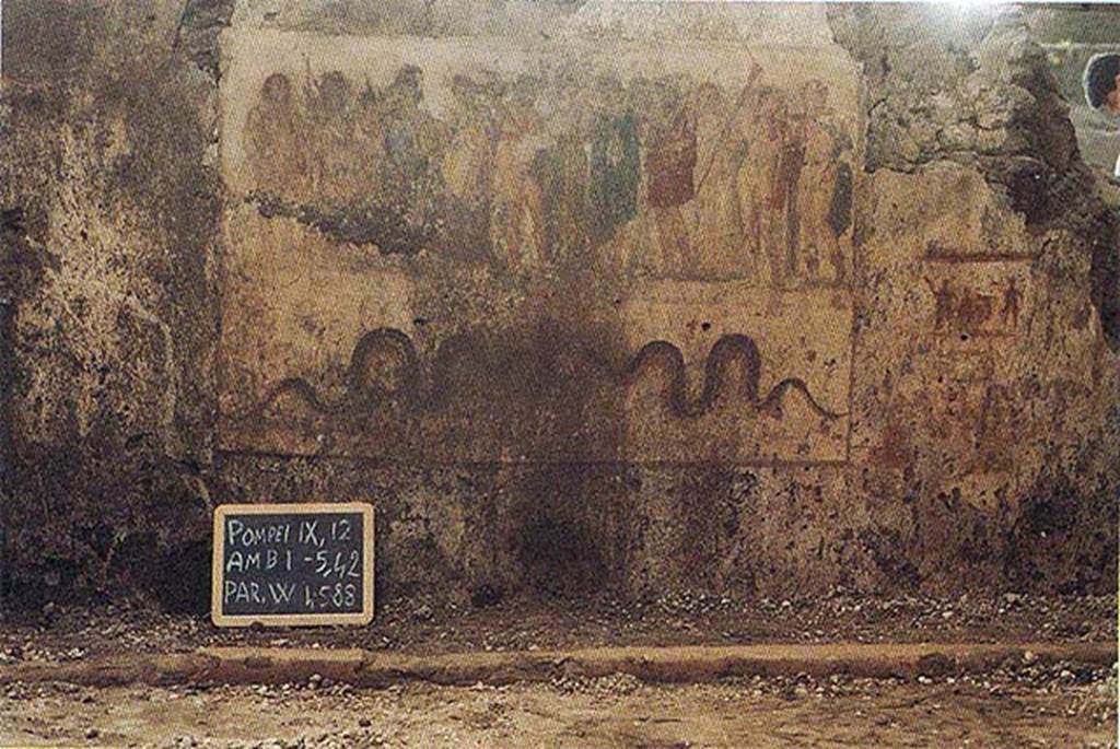 IX.12.6 Pompeii. 1988. Room 6, west wall of internal garden.  
Lararium painting during excavation, showing Hercules being presented to twelve gods in the upper part. 
Underneath are 2 serpents approaching an altar.
To the right are the remains of a possible preparatory sketch for a lararium painting?
The garden wall and masonry altar behind it have not yet been excavated.
See Nappo, S., 1998. Pompeii: Guide to the lost City.  London: Weidenfield and Nicolson. (p.57).
See Varone A in Ercolano 1738 to 1988. Roma: L’Erma di Bretschneider, pp. 617ff.
