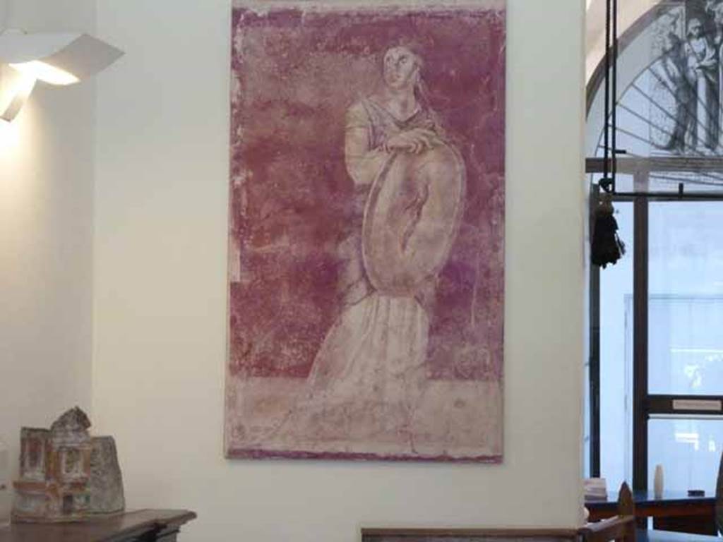 Villa of P Fannius Synistor at Boscoreale. May 2010. Room H, triclinium, panel at north end of east wall. Fresco copy in Naples Museum, of standing woman holding a gold shield.