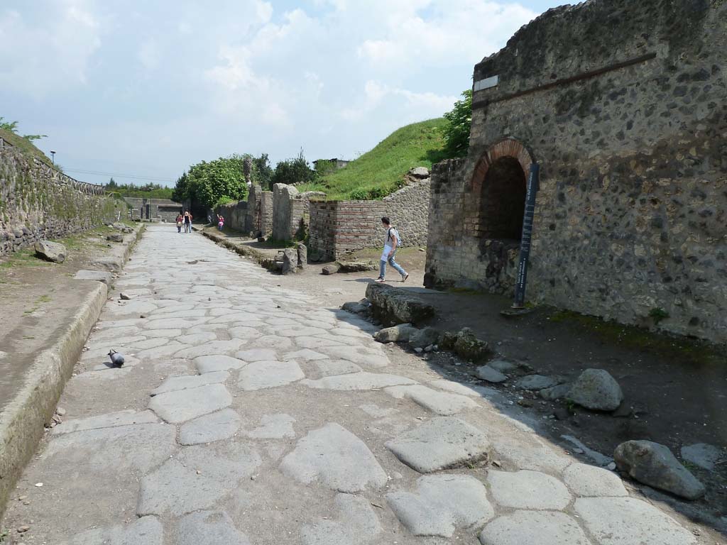 Pompeii II.4.7a. May 2010. Street shrine on north-east corner of II.4.
Looking east along Via dell’Abbondanza towards the junction with Vicolo dell’Anfiteatro.
According to Garcia y Garcia, two bombs fell on the north-east corner of this insula on 19th September 1943.
This damaged the perimeter wall on the Via dell’Abbondanza and the niche, which was then restored.
See Garcia y Garcia, L., 2006. Danni di guerra a Pompei. Rome: L’Erma di Bretschneider. (p.45-6).

