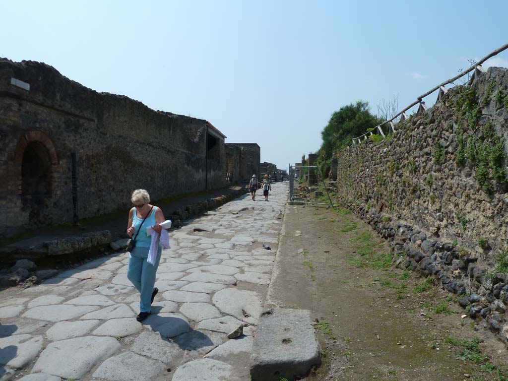 Pompeii II.4.7a. May 2010. Looking west past the street shrine along Via dell’Abbondanza.