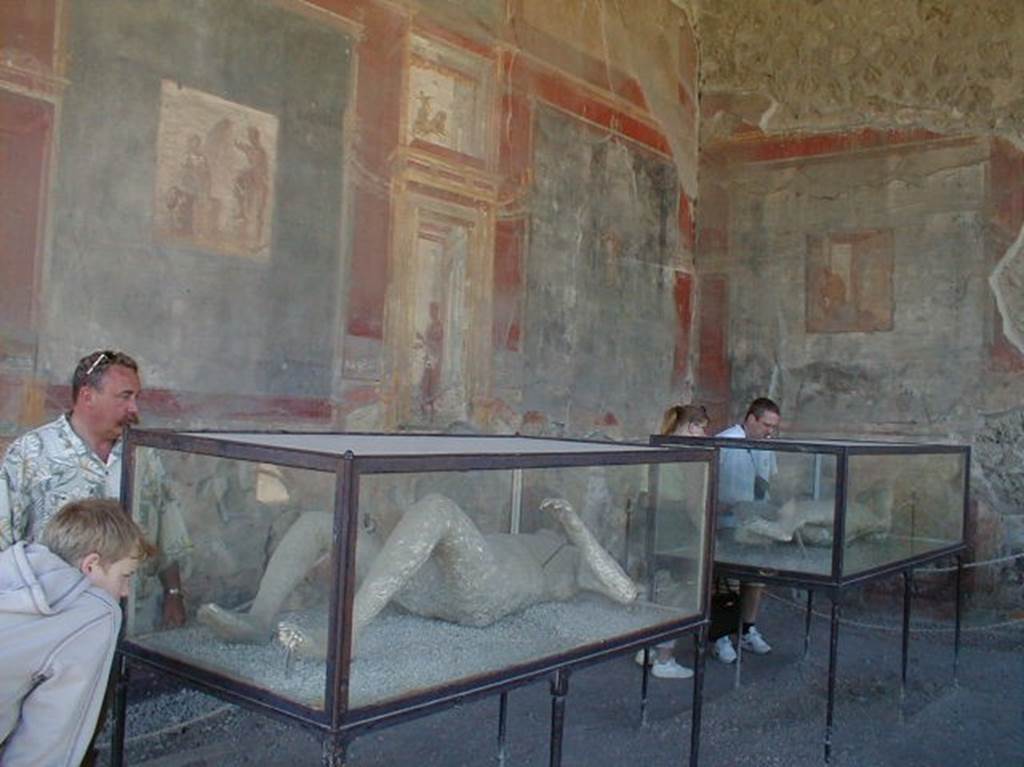 VII.9.7 and VII.9.8 Pompeii. May 2004. Victim number 12 (front) in display case in Macellum.