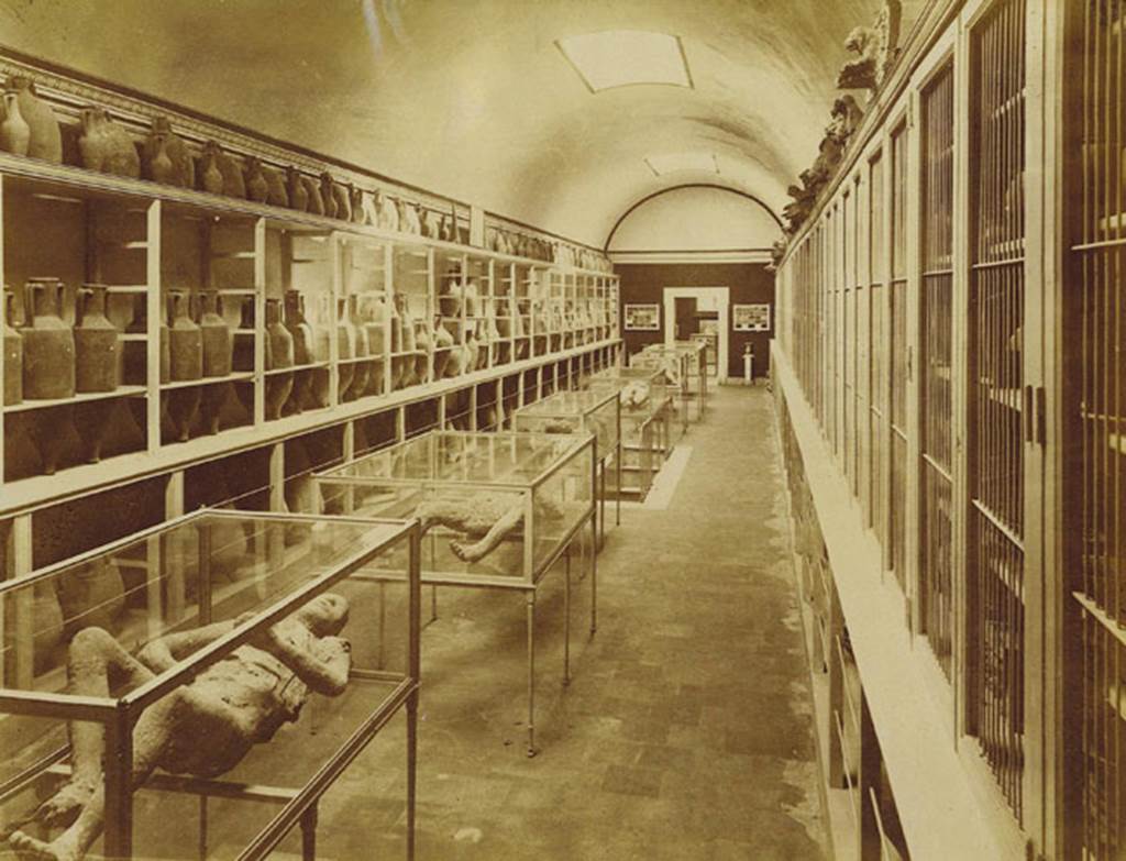 Victim number 9, on left at front, interior of Pompeii Museum before 1889, (Room II). Photo: Edizioni Brogi.
Photo courtesy of Eugene Dwyer.
According to Dwyer, (p.99), 
starting from the left case, Man no.9, Brogi 5573;
Man no.6, Brogi 5574;
Man no.1, Brogi 5575;
Woman no.10, Brogi 5576;
Woman no. 4,  Brogi 5577;
Two women nos. 2 & 3, Brogi 5578;

Room III, Sick Man, no.7, Brogi 5579;
Watchdog, no.8, Brogi 5580.
(the watchdog was later removed to Room II). 
See Dwyer, E., 2010. Pompeii’s Living Statues. Ann Arbor: Univ of Michigan Press, (p.94).

In his description of this plaster-cast in his Guida di Pompei, 1877, Fiorelli described –
“Another man [no.9], on his back, with his legs and arms drawn up, protected by a cloak and sandals. (Reg. VI, Ins. XIV, via nona).”
See Fiorelli, Guida di Pompei, [Rome, 1877,] p.88-89. 
(Note: Fiorelli wrote that victim 9 was found in Reg.VI, XIV, via nona, and that victim 10 was found at Reg. VI. XIV, cardo, and yet they had been found together).
