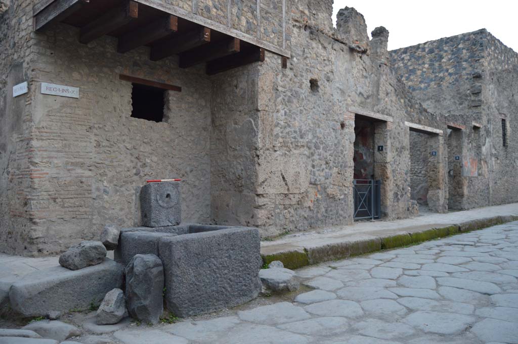Fountain at I.10.1 Pompeii. April 2017. 
Looking towards corner of Vicolo di Menandro (on right) at junction with Vicolo di Paquius Proculus (on left). .
Photo courtesy Adrian Hielscher.
