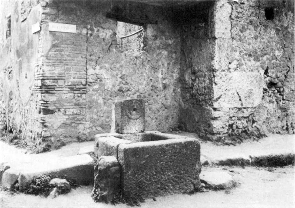 Fountain at I.10.1, Pompeii, c.1974. Fountain with relief of plate and with blocked up shop at rear.