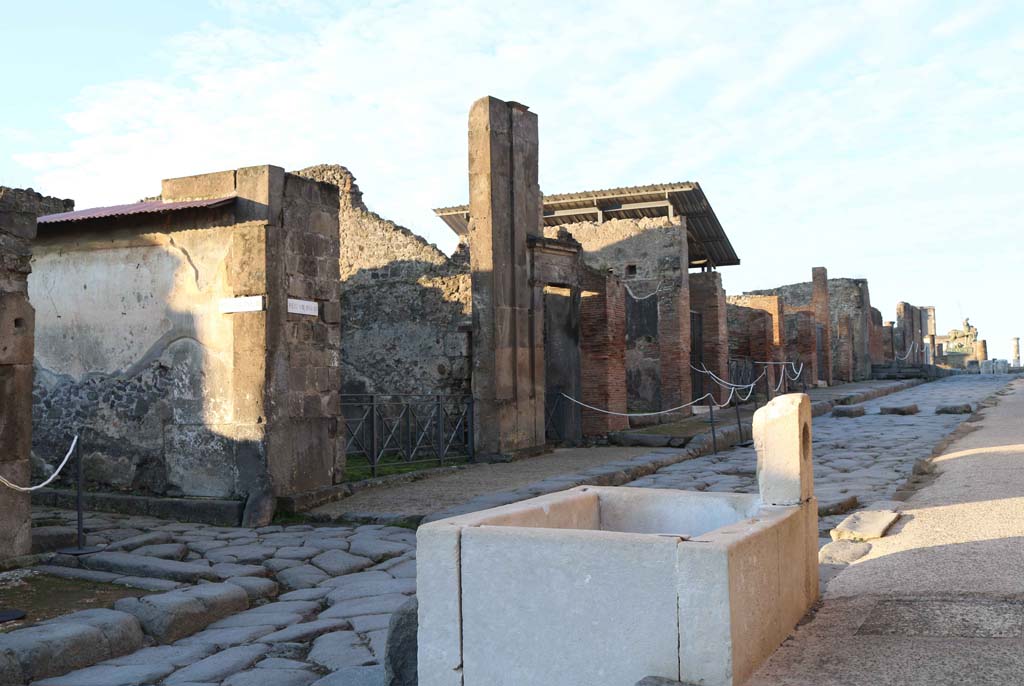 Via dell’Abbondanza, south side, Pompeii. December 2018. 
Looking south-west across fountain at VII.9.67/68, towards north side of Insula VIII.3. Photo courtesy of Aude Durand.

