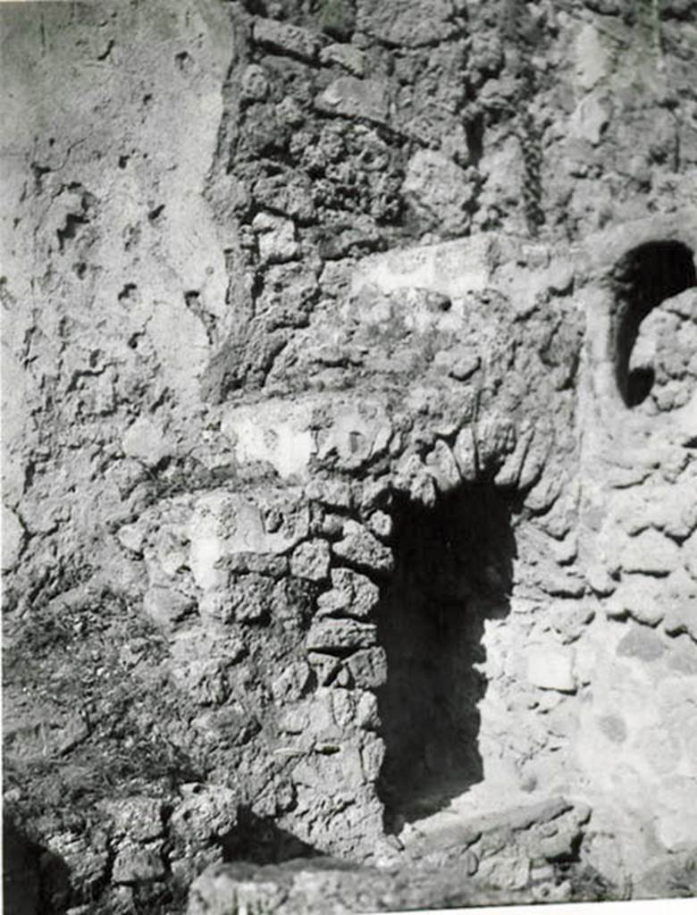 I.2.28 Pompeii. 1935 photo taken by Tatiana Warscher.  North-east corner of garden area, with steps to upper floor and recess below.
See Warscher T., 1935. Codex Topographicus Pompeianus: Regio I.2. (no.57), Rome: DAIR, whose copyright it remains.
According to Warscher, “Il lato orientale del peristilio. La scala con sottoscala che conduceva al primo piano e la finestra ovale che illuminava la cucina “k”.
(translation: “The east side of the peristyle. The stairs with understairs, that lead to the first floor, and the oval window that lit the kitchen “k”.)
