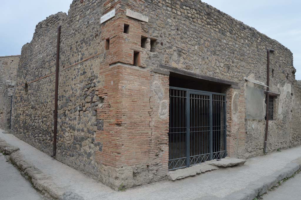 I.8.15 Pompeii. December 2018. Looking north to entrance doorway on Via di Castricio. Photo courtesy of Aude Durand.
According to PPM, 
“All of the south-west area of the insula 8 was reserved for commercial activity and sales, since part of this property was used as a caupona with its characteristic sales podium in the entrance room, and with the rooms for the customers (at the rear on the left).
The eastern part, with the neighbouring dwelling at I.8.14, was used as a “colouring” plant. No colours had been found here because the site was not functioning in 79AD, but the oven of small dimensions with its slow drying plate, three manual reels/mules and nine mortars with pestles left in the room, leave no doubt about its use.  
This workshop probably had the same proprietor as the caupona, in that the entrance doorway opening into it, opened from the caupona.”
See Carratelli, G. P., 1990-2003. Pompei: Pitture e Mosaici: Vol. I. Roma: Istituto della enciclopedia italiana, p. 844. 
