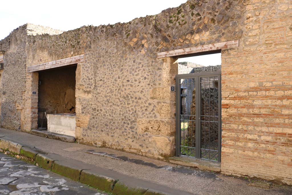 I.9.3 Pompeii, on right, and I.9.4, on left. December 2018. 
Entrance doorways on south side of Via dell’Abbondanza. Photo courtesy of Aude Durand.
