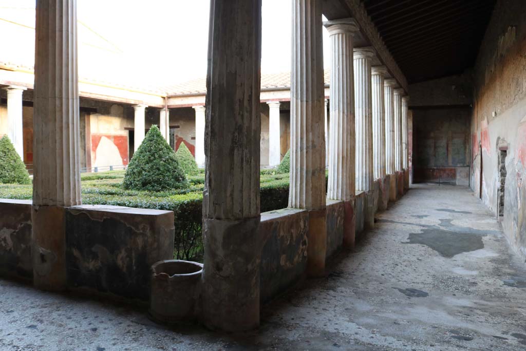 I.10.4 Pompeii. December 2018.
Looking south-east across peristyle, and south along west portico towards south-west corner. Photo courtesy of Aude Durand.
On both the garden and portico sides of each wall between every two columns are scenes of hunts, and paintings of birds and plants.
On the left is an embedded puteal above a cistern mouth. 
On both the garden and portico sides of each wall between every two columns are scenes of hunts and paintings of birds and plants.

