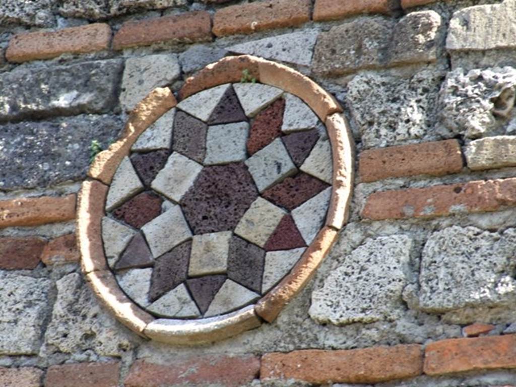 I.10.9 Pompeii.  March 2009.  Coloured terracotta decorated circular plaque on north side of entrance. 
