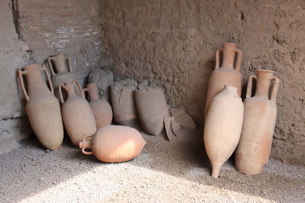 I.10.14, Pompeii. September 2021. 
Amphorae in south-east corner, on south side of blocked doorway. Photo courtesy of Klaus Heese.
