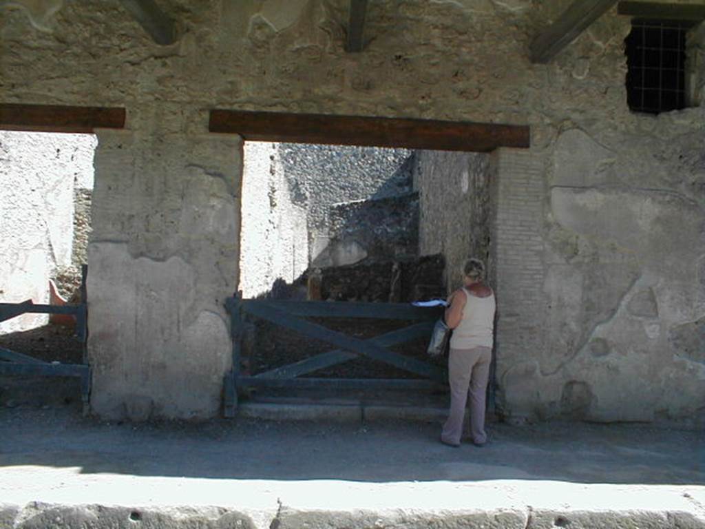 I.11.2 Pompeii. May 2005. Entrance doorway, looking south.
According to Della Corte,  “Reg. II, ins.1, on high between doorways 1 and 2, a window was found (0.80m wide x 1.20m high), protected by a grating which remains in its place in reasonable state of preservation; beyond the described window and continuing towards the east, and it seems placed above doorways 2 and 3, a large roof was found a little knocked down from its original position, about 6m. long (but the eastern extremity was not yet discovered), and protruding by just over 2m.  At the rear of the wall of the façade of doorway 1, definitely in their place were the remains of the basins/tubs mentioned last month, putting all the fragments of one of them back into its place with its bottom. "  See Notizie degli Scavi, 1913, p.220.
(Reg. II, ins. 1. Tra i vani 1 e 2 in alto, si e scoperta una finestra (larga 0.80m. alta 1.20m) protetta da inferriata che resta tuttora al suo posto in discreto stato di conservazione; oltre la descritta finestra, procedende sempre verso oriente, e quindi imposta sul vani 2 e 3 come pare, si era rinvenuta, di poco abbattuta dalla sua originaria posizione, una grande tettoia, lunga per ora (non se ne era ancora scoperta l’extremita orientale) 6m, e sporgente per poco piu di m.2.  A tergo del muro di facciata del vano 1 si sono definitivamente assicurati al posto loro gli avanzi delle vasche accennate il mese scorso, rimettendo a posto interamente i frammenti di una di esse col relativo fondo.”)
