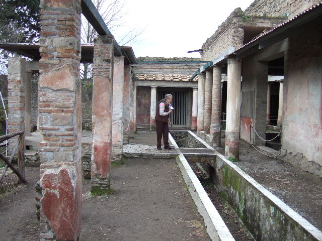 II.2.2 Pompeii. May 2016. Room “l”, garden. Looking north to marble steps in the nymphaeum at the northern end of the lower euripus. A white statuette of a cupid with a mask has now been replaced there.  Photo courtesy of Buzz Ferebee.
