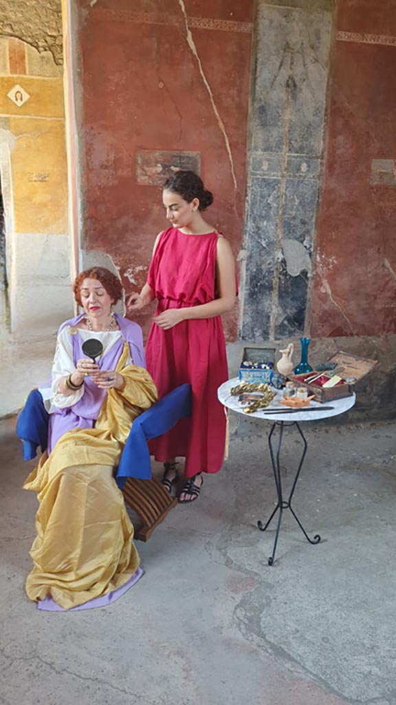 II.3.3 Pompeii. 8th June 2024. 
Room 11, north portico, actors portraying slave attending to mistress’s hair and beauty. Photo courtesy of Giuseppe Ciaramella.
Historical reconstruction entitled L’altra Pompei prende vita (The other Pompeii comes to life).
