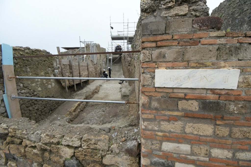 V.2.20 Pompeii. June 2018. Entrance to V.2.20 is the doorway on the Vicolo dei Balconi where the three people are.