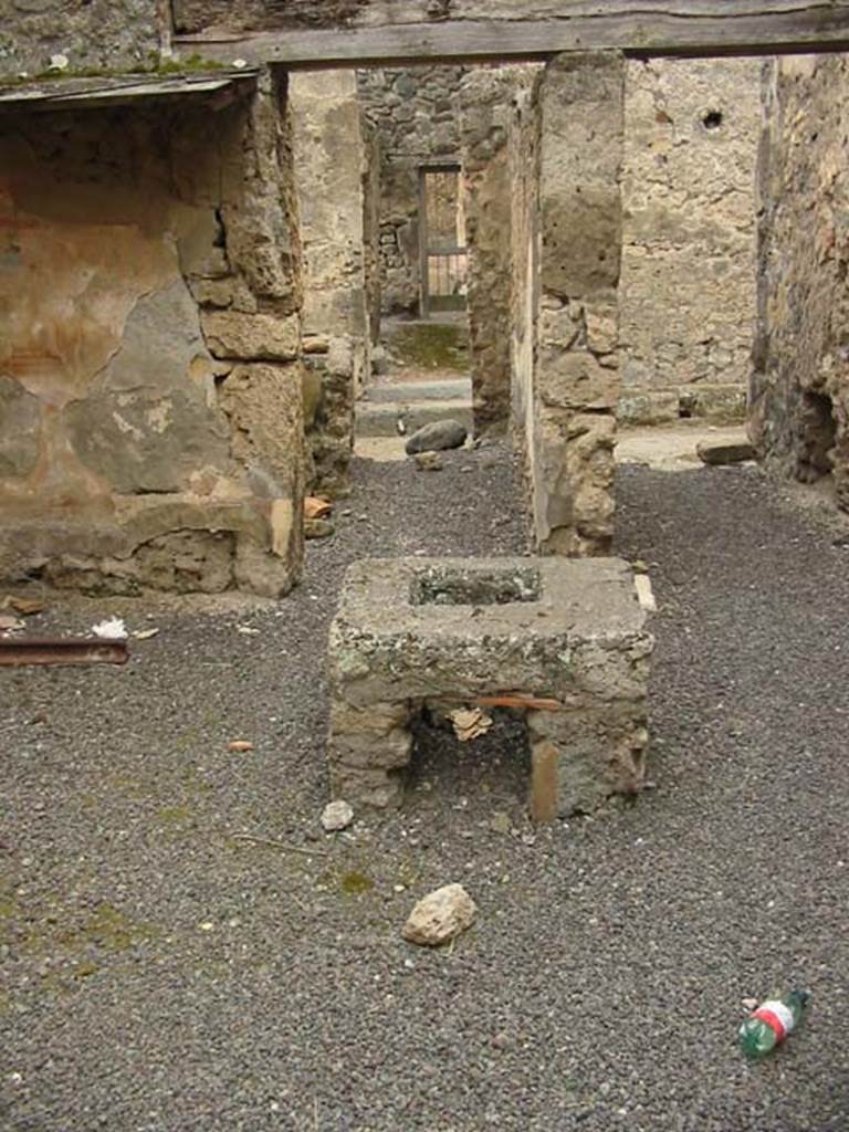V.2.b/c Pompeii. May 2003. Room “b”. Stove in centre of room.
It was a covered in reddish stucco (with addition of brick dust), and in the centre was fitted a quadrangular lead jar with a round mouth.
Looking west towards entrance to V.2.b (on left) and V.2.c (on right).    
Photo courtesy of Nicolas Monteix.
