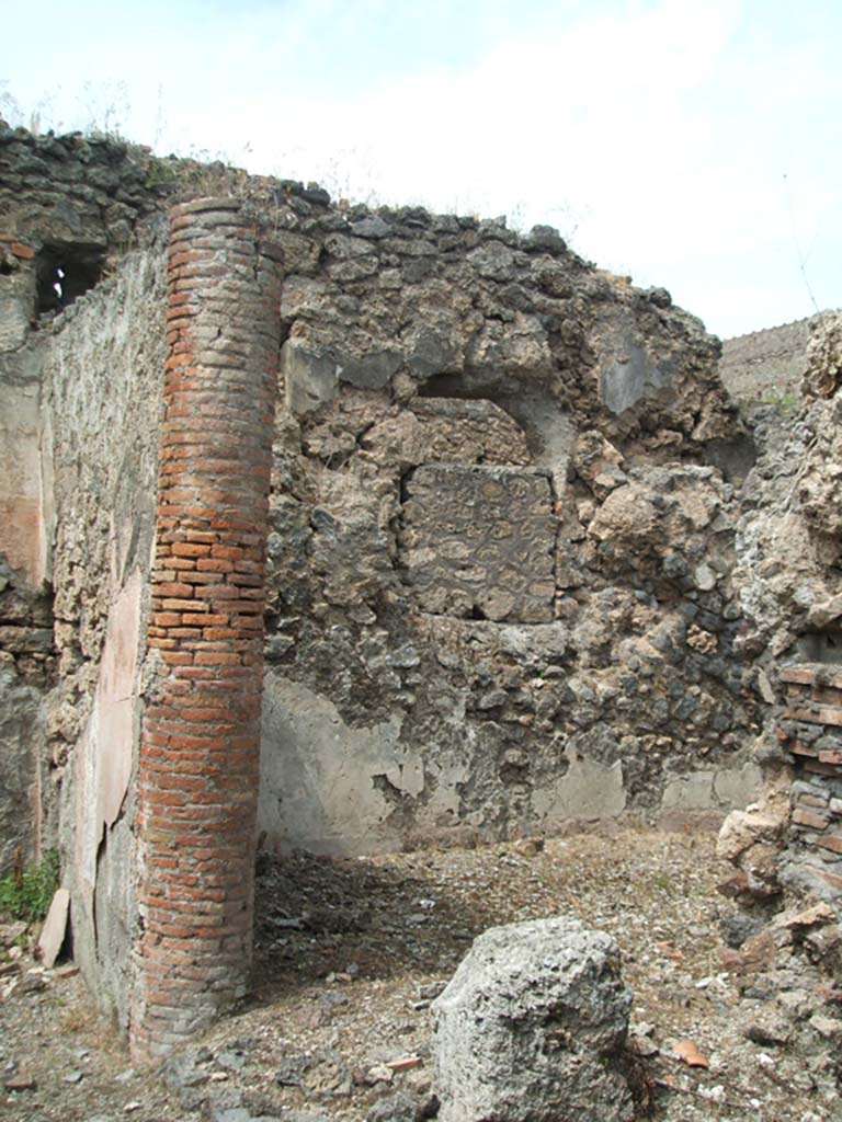 V.2.d Pompeii. May 2005. Looking towards oecus “f” on north side of vaulted passageway.
On the left is the east side of the ala “c”.
According to PPM, in ancient times the atrium would have had a roof supported by brick columns which can be seen, above, in the wall between the ala and oecus.
According to Boyce, there were two lararia in the house.
One on the east wall of the left ala of the atrium, within a panel (1.03m high, and 1.35m wide) was painted a single yellow serpent.
The serpent was moving left amidst plants towards an altar furnished with two eggs and a pine cone. 
Above there may have originally been figures, but the plaster has now fallen.
See Boyce G. K., 1937. Corpus of the Lararia of Pompeii. Rome: MAAR 14. (p.36, nos.101 and 102)
See Bullettino dell’Instituto di Corrispondenza Archeologica (DAIR), 1885, p.254.
